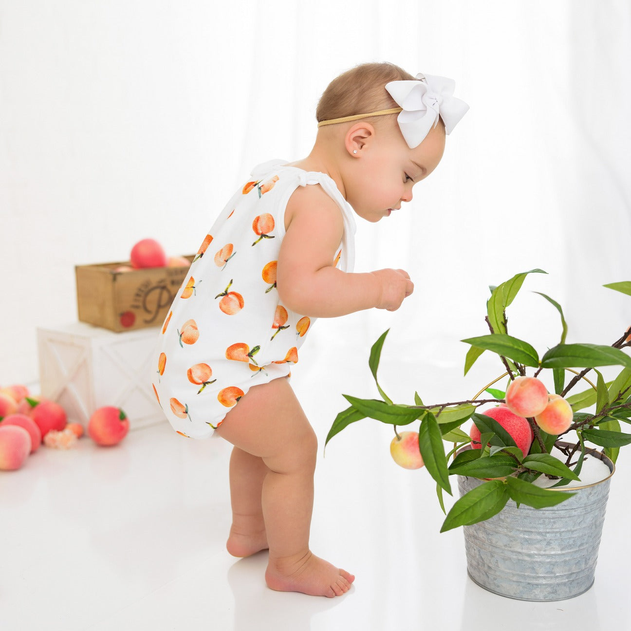 Baby wearing a white peachy romper. perfect for summer